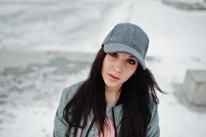 fille brune élégante en casquette grise, style de rue décontracté le jour de l'hiver. photo