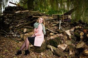 jeune fille blonde au manteau rose posé sur fond de souches de bois. photo