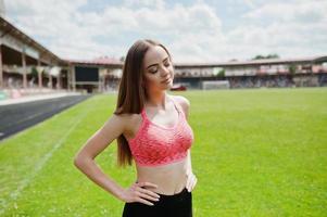 fitness fille sportive en tenue de sport dans un stade de football sports de plein air. séance d'entraînement de femme sexy heureuse sur le fond de l'herbe verte. photo