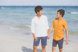 portrait homosexuel jeune couple asiatique debout ensemble sur la plage en été, asie gay main dans la main aller en mer pour les loisirs et se détendre avec romantique et heureux en vacances en mer, lgbt avec concept juridique. photo