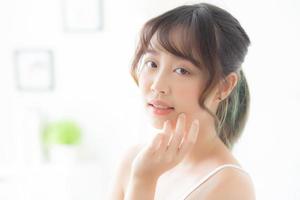 beau portrait femme asiatique maquillage de cosmétique, fille main toucher joue et sourire attrayant, beauté du visage parfaite avec bien-être dans la chambre avec concept de soins de la peau et de soins de santé. photo