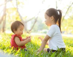 beau jeune enfant asiatique assis jouant en été dans le parc avec plaisir et gai sur l'herbe verte, activité des enfants avec détente et bonheur ensemble sur le pré, la famille et le concept de vacances. photo