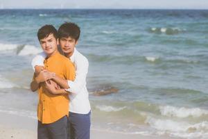 portrait homosexuel jeune couple asiatique debout câlin ensemble sur la plage en été, asie gay va tourisme pour les loisirs et se détendre avec romantique et bonheur en vacances en mer, concept lgbt. photo