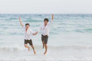 portrait homosexuel jeune couple asiatique courir et sauter avec gaieté ensemble sur la plage en été, asie gay faisant du tourisme pour les loisirs et se détendre avec bonheur en vacances en mer, concept juridique lgbt. photo