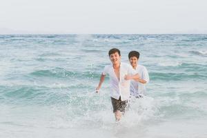 portrait homosexuel jeune couple asiatique courant avec gai ensemble sur la plage en été, asie gay faisant du tourisme pour les loisirs et se détendre avec bonheur en vacances en mer, concept juridique lgbt. photo