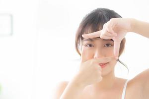 belle jeune femme asiatique soins de la peau des yeux et cadre de geste avec la main pour la vision, beauté visage fille asie cosmétique et maquillage pour la santé, vue de la femme pour le bien-être avec fraîcheur. photo