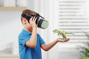 un garçon avec des lunettes vr projette un dinosaure sur son bras. le concept d'utilisation de la réalité virtuelle dans l'éducation