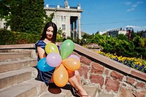 magnifique fille brune dans la rue de la ville avec des ballons à portée de main. photo