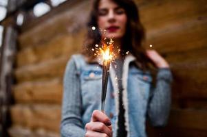 portrait de jeune fille brune en veste jeans avec feux de bengale dans les mains. photo