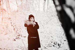 belle fille brune en vêtements chauds d'hiver. modèle sur veste d'hiver et chapeau noir. photo