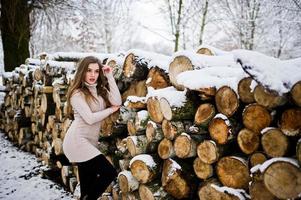 belle fille brune en vêtements chauds d'hiver. modèle sur pull d'hiver près de la souche. photo