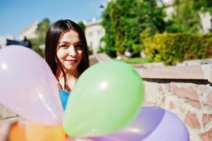 magnifique fille brune dans la rue de la ville avec des ballons à portée de main. photo