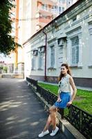 une fille élégante et bouclée porte une jupe en jean bleu, un chemisier et écoute de la musique à partir d'un casque téléphonique. portrait dans les rues de la ville. photo