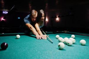 femme en robe jouant au billard avec un homme dans un pub. photo