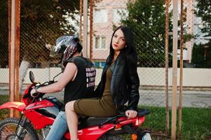 femme en robe et veste en cuir à moto avec un autre homme. photo