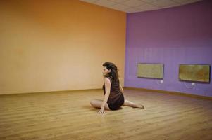 brune frisée plus modèle de taille faisant des acrobaties à la salle de danse. photo