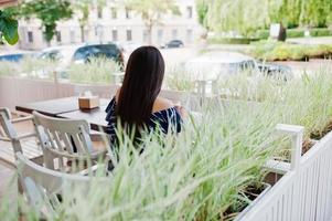 magnifique fille brune assise sur la table au café avec une tasse de café et de boisson. photo