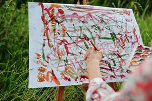 photo en gros plan de peinture à la main féminine sur le papier avec des aquarelles.