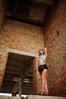les filles portent des shorts avec de gros écouteurs dans une usine abandonnée avec des murs de briques. photo