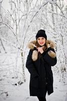 belle fille brune en vêtements chauds d'hiver. modèle sur veste d'hiver et chapeau noir. photo