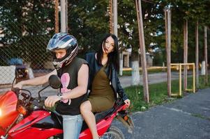 femme en robe et veste en cuir à moto avec un autre homme. photo