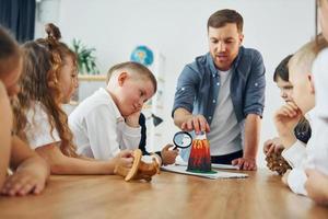 regardant le modèle de volcan. groupe d'enfants élèves en classe à l'école avec professeur photo