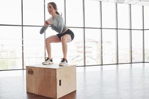 sur le bord de la boîte. une jeune femme sportive a une journée de remise en forme dans la salle de sport le matin photo