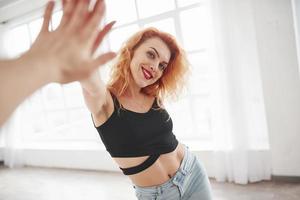 effet miroir. jolie femme rousse posant dans la chambre spacieuse près de la fenêtre photo