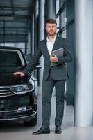 photographie verticale. homme d'affaires barbu élégant et moderne dans le salon automobile photo