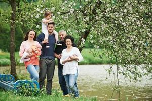 photo de famille. portrait complet de personnes gaies debout à l'extérieur ensemble près du lac