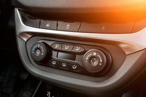 la console de commande centrale sur le panneau à l'intérieur de la voiture gros plan avec climatisation et système audio et un trou pour le cd et le bouton d'urgence en gris et noir.