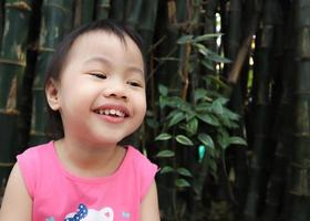 petite fille asiatique souriant joyeusement à l'extérieur à la recherche sur l'espace de copie. photo