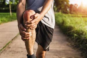 les hommes blessés par l'exercice utilisent vos mains pour tenir vos genoux au parc photo