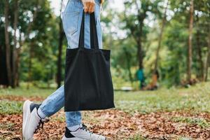 femme tenant un sac en coton noir sur fond de nature photo