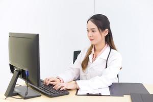 belle femme médecin asiatique tape sur un clavier pour enregistrer des informations sur l'ordinateur. nouveau concept normal et de soins de santé. photo
