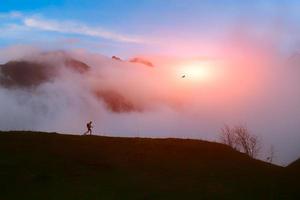 randonneur solitaire dans les montagnes au coucher du soleil avec des nuages photo