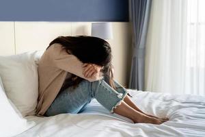 jeune femme solitaire se sentant déprimée et stressée assise dans la chambre sombre, émotion négative et concept de santé mentale photo