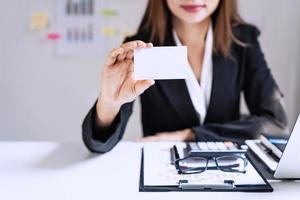 femme d'affaires souriant et montrant une carte de visite vierge à son bureau photo