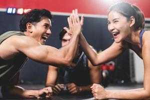 entraîneur personnel aidant une jeune femme à faire de l'exercice dans la salle de sport, à faire de l'exercice en fitness, à un corps sain et actif dans le mode de vie sportif, à la musculation d'une fille heureuse avec des vêtements de sport photo