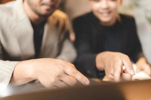 jeune homme d'affaires asiatique travaillant sur des documents papier dans un bureau moderne, un homme professionnel est heureux de démarrer une entreprise avec une nouvelle personne travaillant en équipe en utilisant un plan d'affaires pour travailler photo