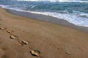 empreintes de pas dans le sable sur les rives de la mer méditerranée dans le nord d'israël photo