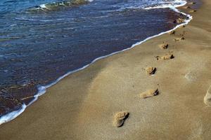 empreintes de pas dans le sable sur les rives de la mer méditerranée dans le nord d'israël photo