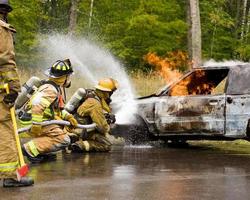 deux pompiers pulvérisant une voiture en feu. photo