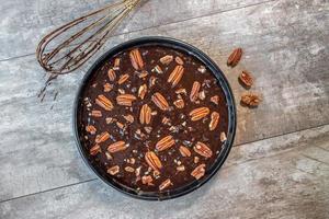 mise à plat d'une poêle ronde de pâte à brownie au chocolat avec pacanes photo