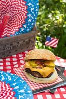 4 juillet cheese burger avec drapeau américain sur table de pique-nique à l'extérieur photo