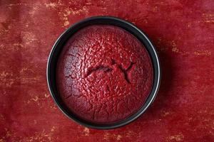 Vue de dessus du gâteau au chocolat rond en velours rouge cuit dans une poêle sur fond rouge à plat photo