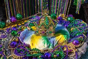 mardi gras king cake surmonté d'une couronne entourée de perles et de décorations photo
