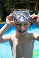 jeune garçon souriant dans des lunettes de natation à la piscine photo