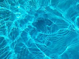 défocalisation aquarelle bleue floue dans l'arrière-plan détaillé de l'eau ridée de la piscine. éclaboussures d'eau, fond de pulvérisation d'eau. photo
