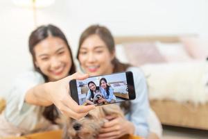 un couple de belles amies asiatiques prenant un selfie avec un chien dans la chambre. photo